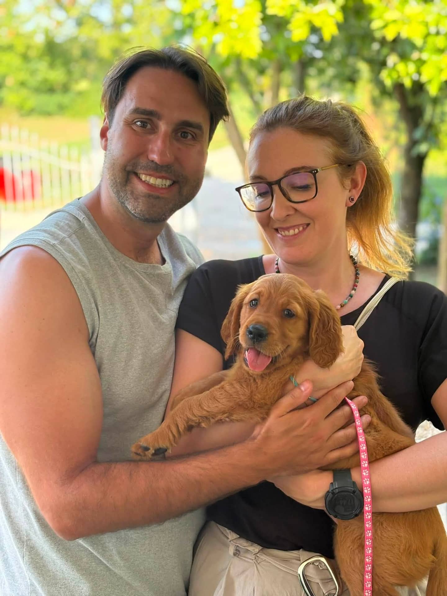 Coppia sorridente tiene in braccio un cucciolo di Golden Retriever